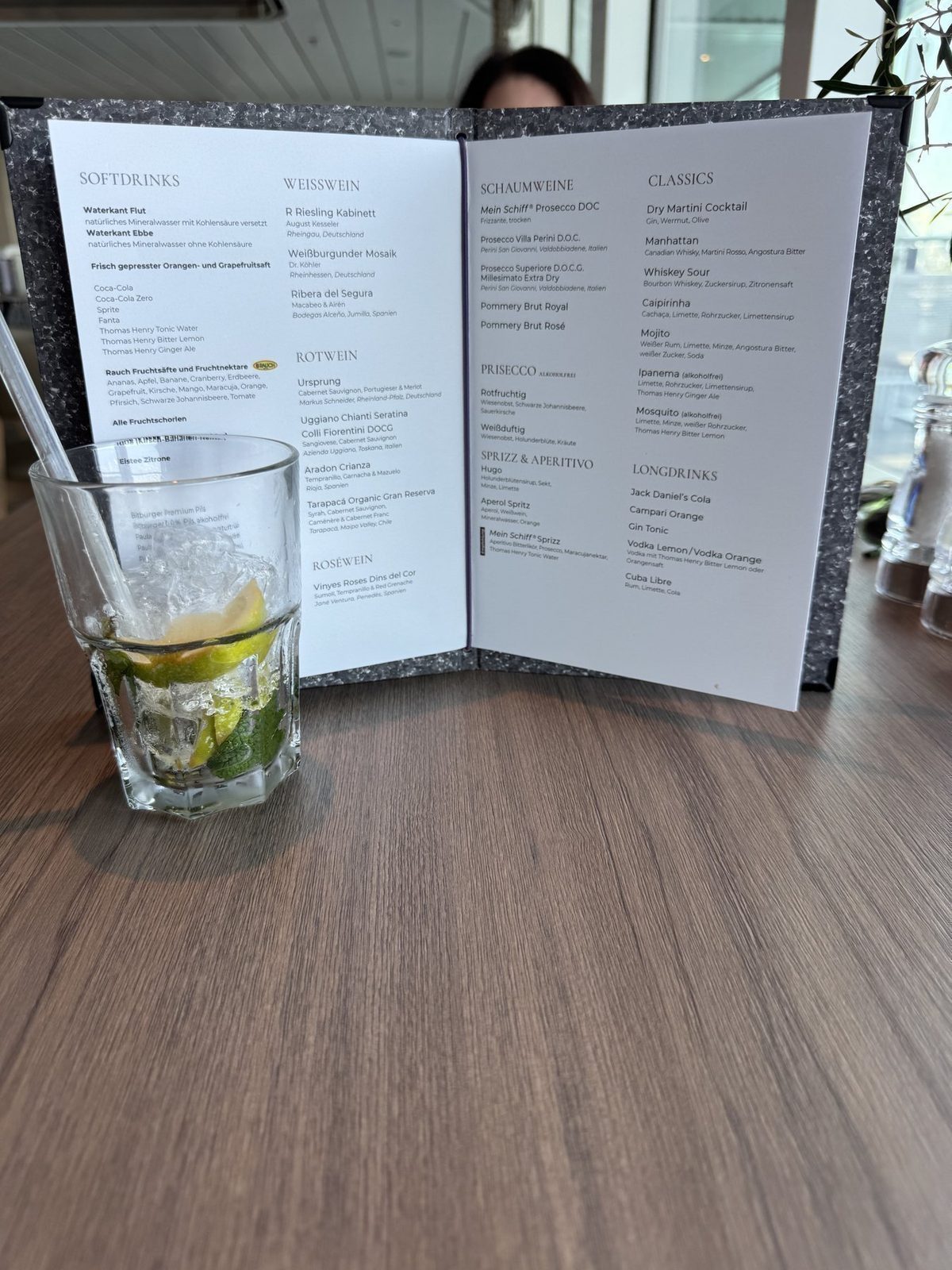Getränk mit Limette auf Holztisch vor Menü