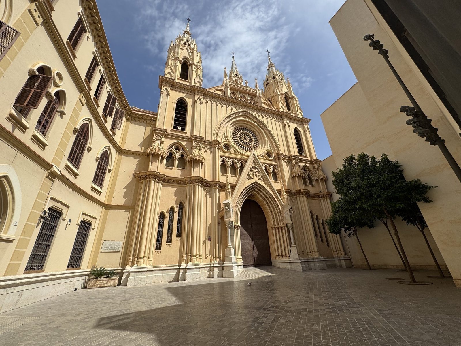 Eine gotische Kathedrale mit markanten Türmen und einem großen Rosettenfenster im Vordergrund