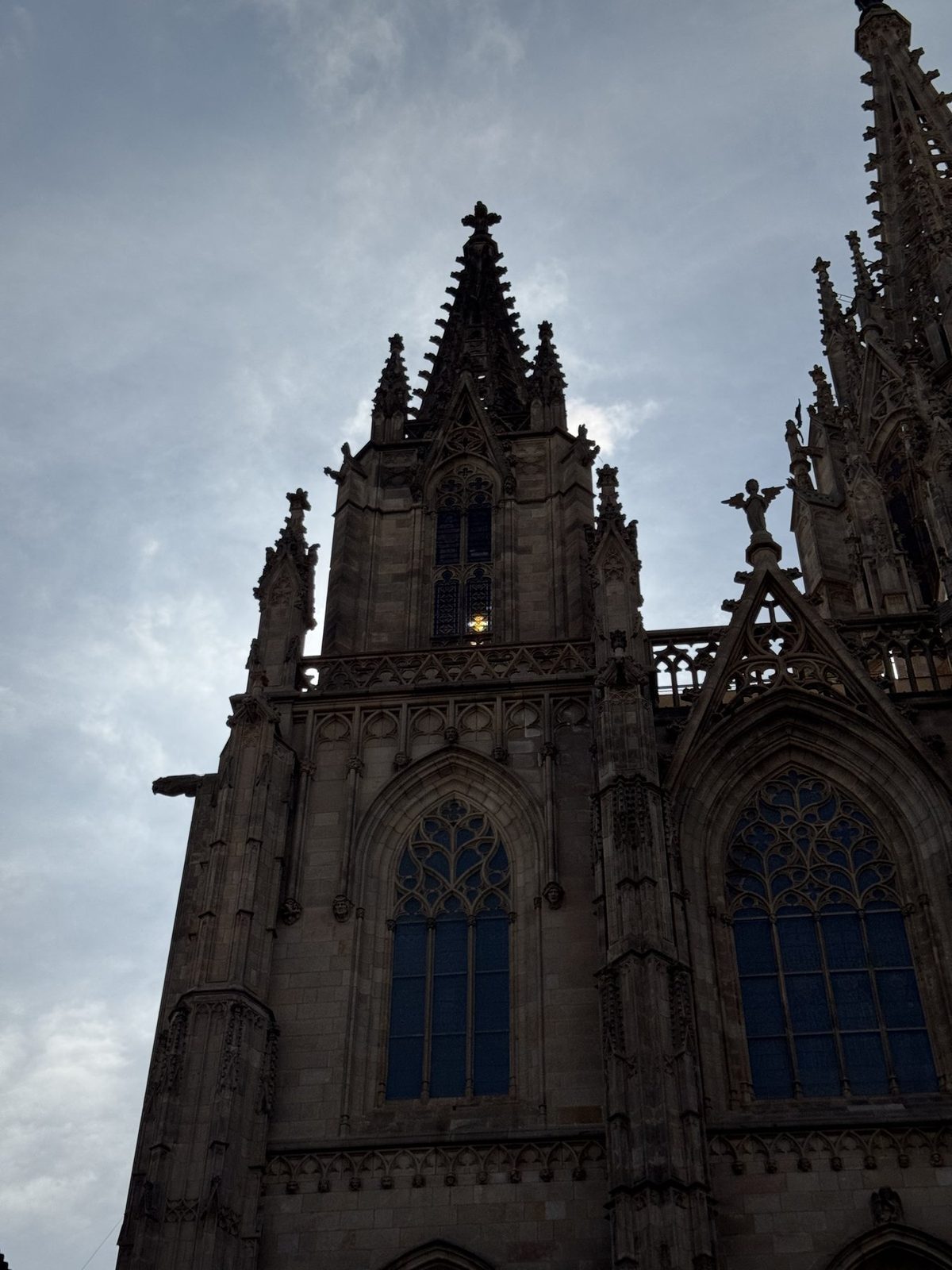 Eine gotische Kathedrale mit markanten Türmen und spitzen Dächern unter einem bewölkten Himmel