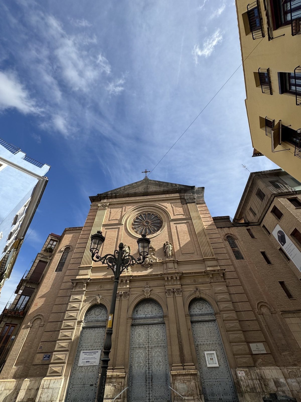 Ein großes Kirchengebäude mit einem markanten Rundfenster über dem Eingang steht unter einem klaren, blauen Himmel