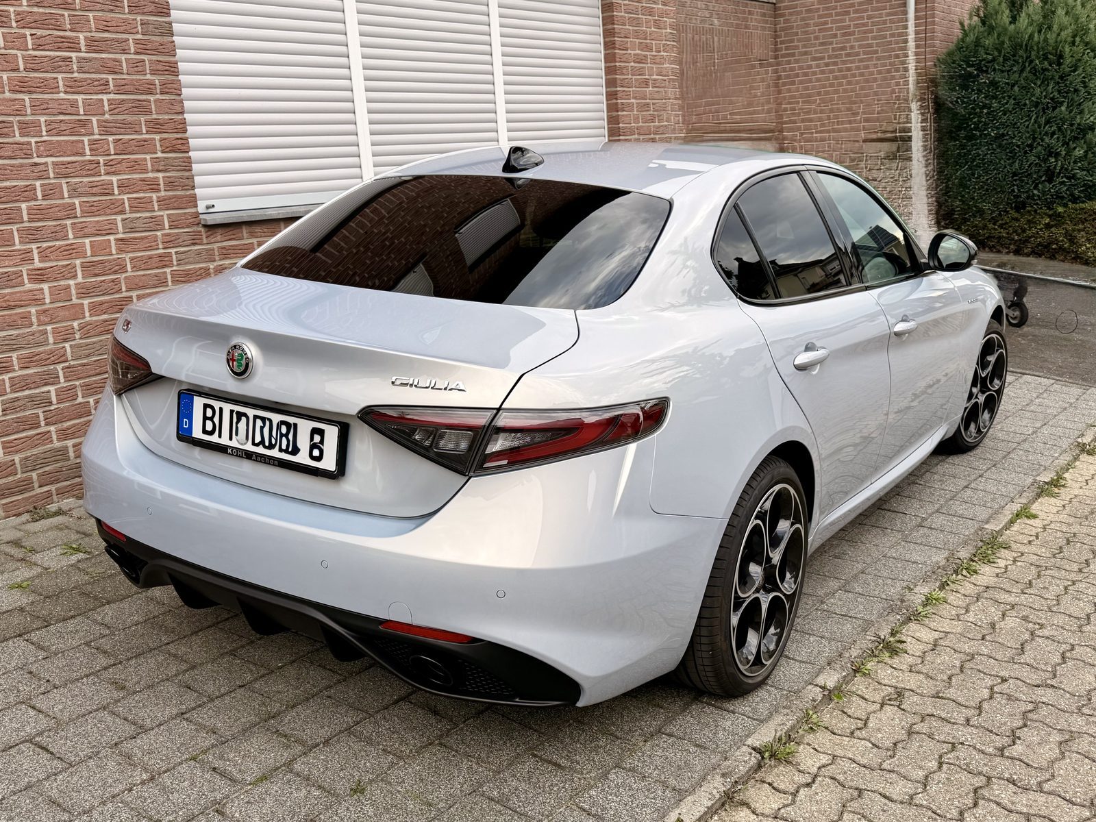 Perla Lunare strahlt auf Alfa Romeo Giulia vor Backsteinmauer geparkt