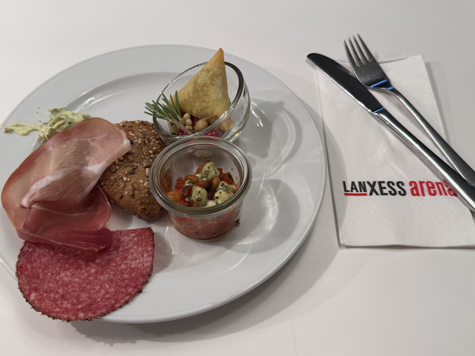 Vorspeise mit leckerer Salami, Schinken, Salatschälchen und Samosas