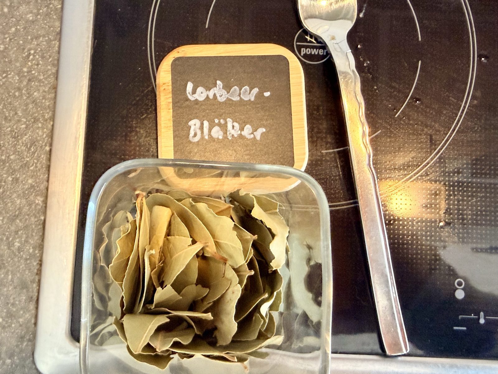 In einem durchsichtigen Glasbehälter liegen trockene Lorbeerblätter