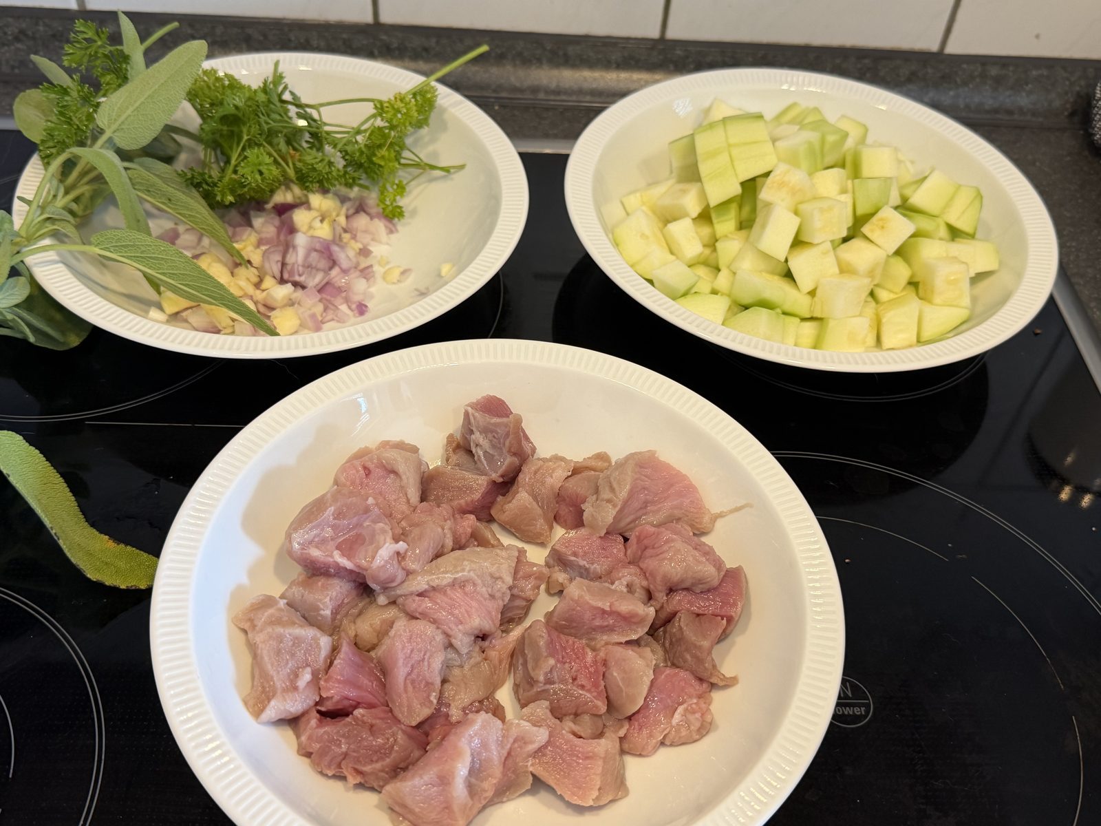 Drei Schalen mit frisch geschnittenen Zutaten stehen auf einer Kochplatte
