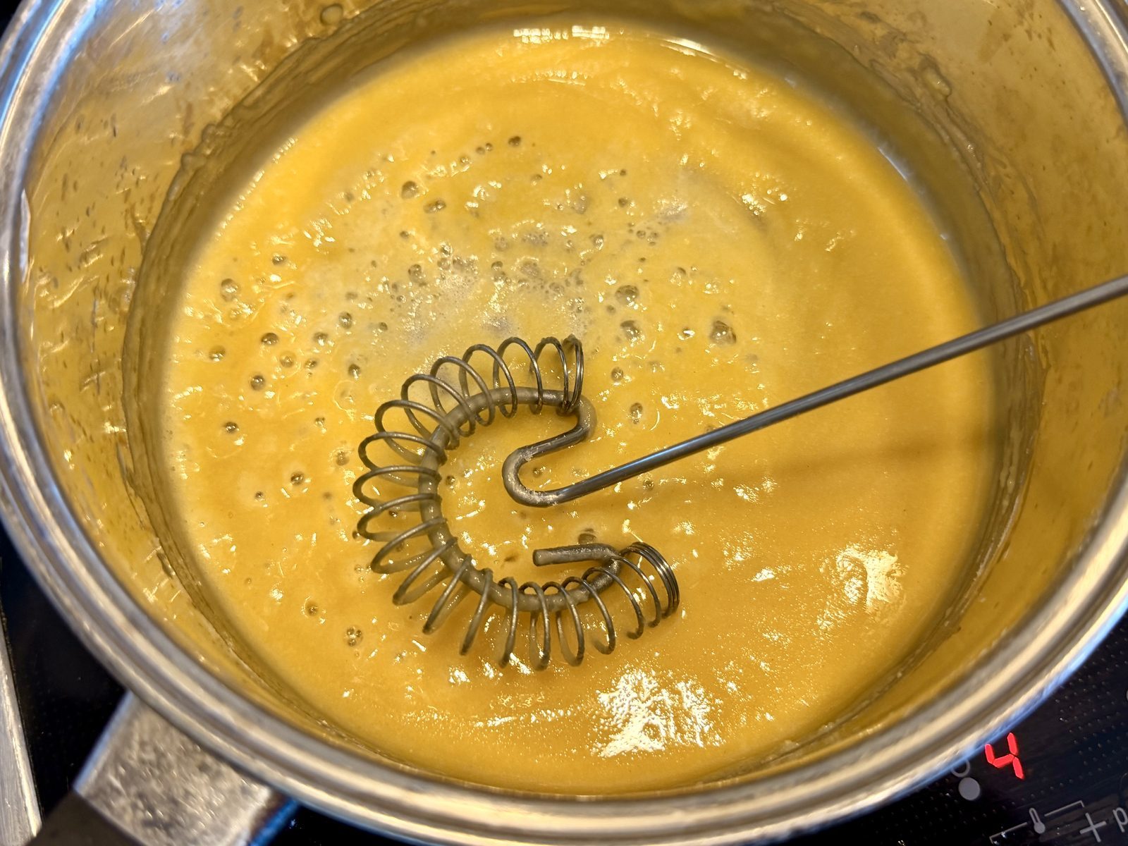 In einer metallenen Pfanne kocht eine gelbe Flüssigkeit, die wie Eiercreme aussieht