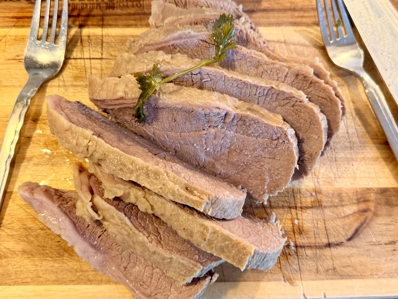 Auf einem Holzbrett liegen mehrere Scheiben gebratenes Fleisch