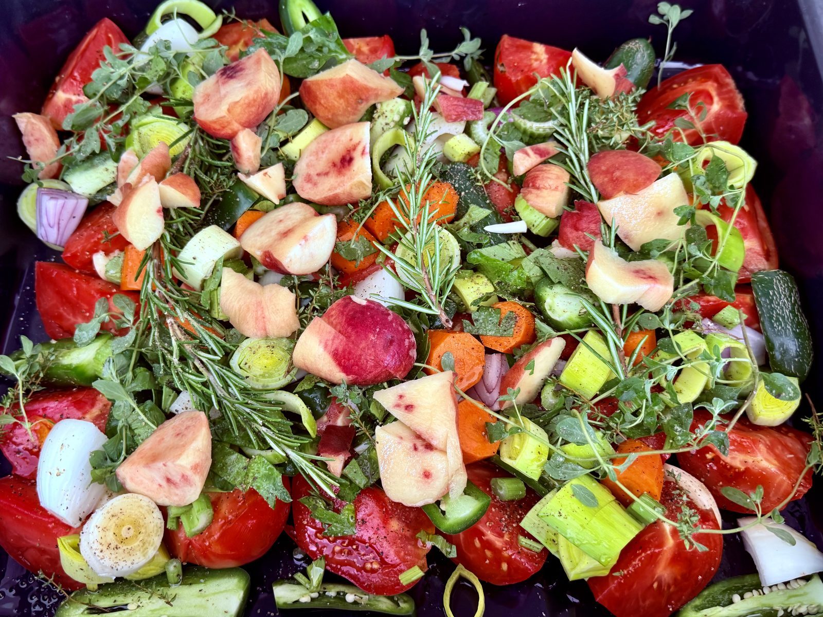 Ein großer, dunkler Topf ist mit einem bunten Mix aus roten Tomaten, rosa