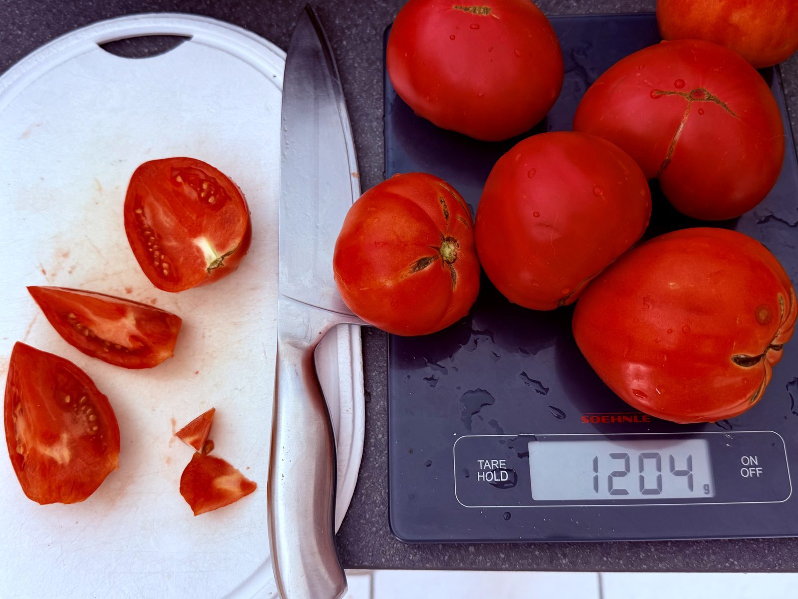 Auf einer Küchenwaage liegen frische Tomaten mit einem Gewicht von 1204 Gramm